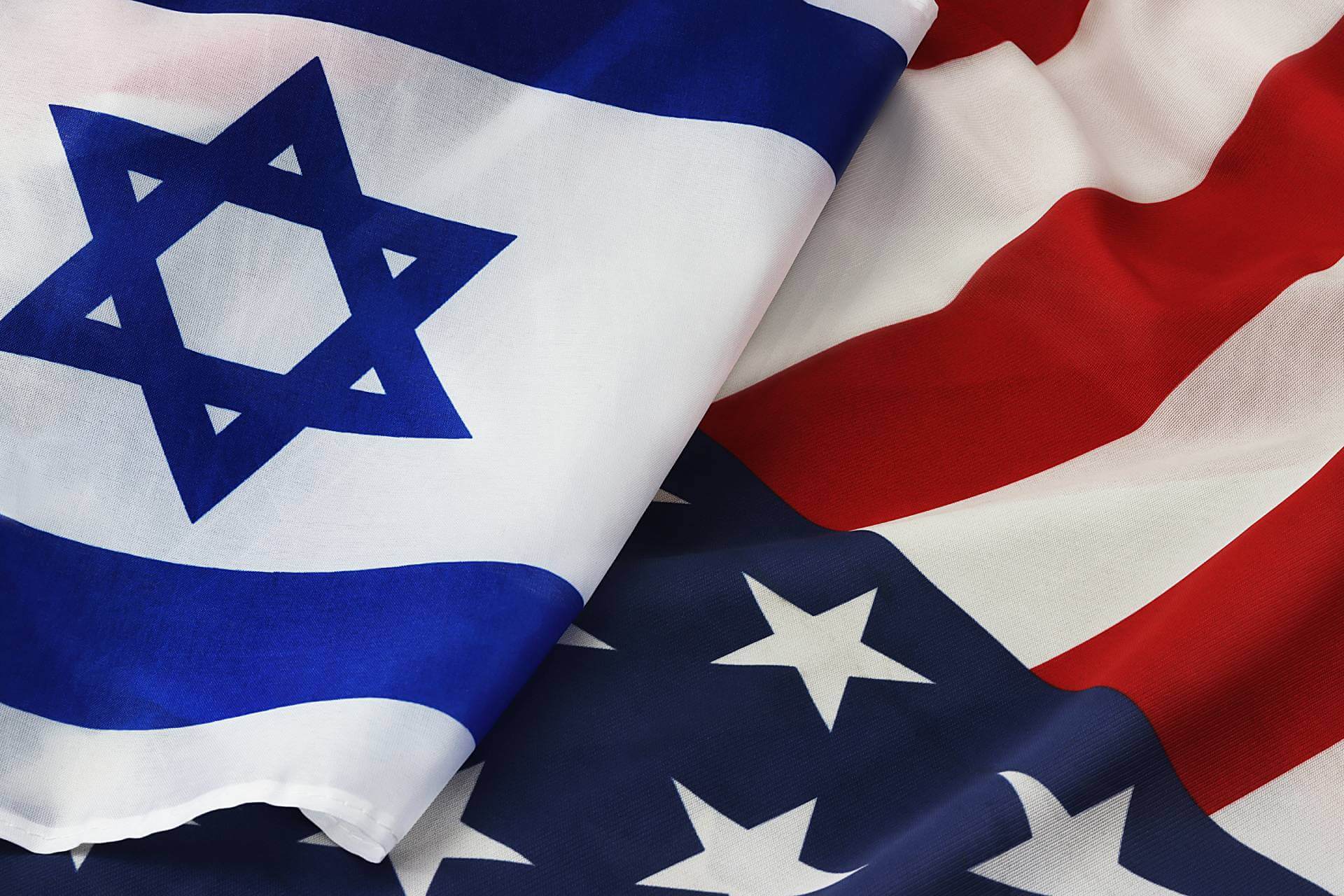 Close-up of intertwined Israeli and American flags symbolizing unity and allied defense.