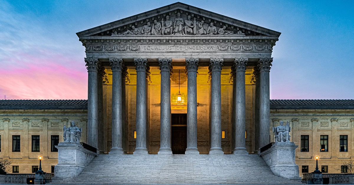 Front view of the U.S. Supreme Court at dusk with glowing interior lights beneath the inscription "Equal Justice Under Law," symbolizing the Court’s ruling affirming parents’ rights to opt their children out of LGBTQ curriculum in public schools.