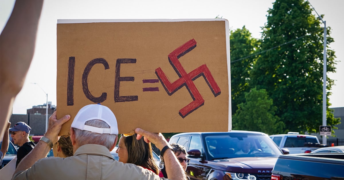 Protest sign compares ICE agents to Nazis using a Swastika symbol