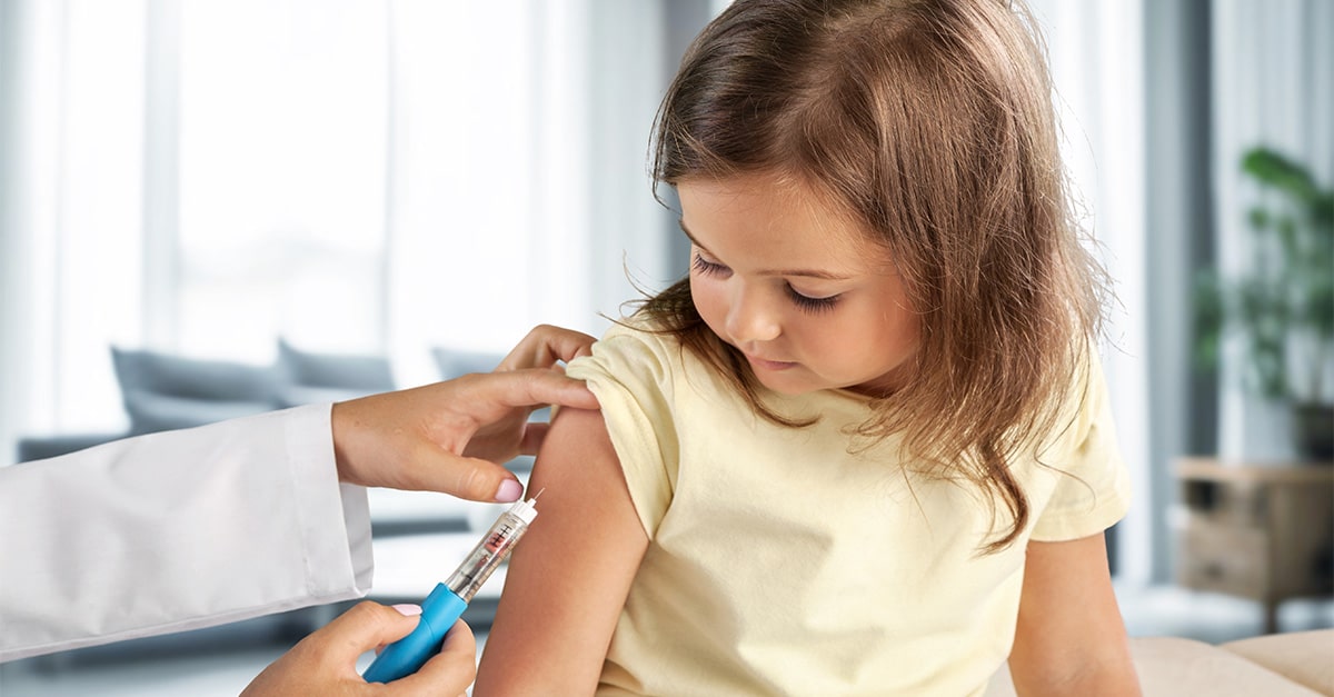 Doctor administers vaccine by arm injection to young girl.