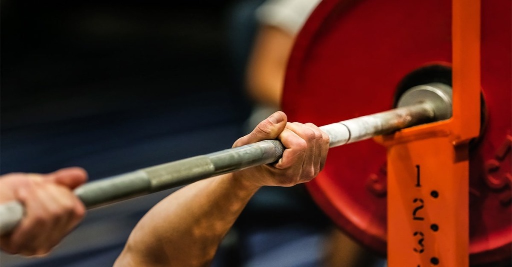 Man lifting barbell loaded with extra heavy discs.