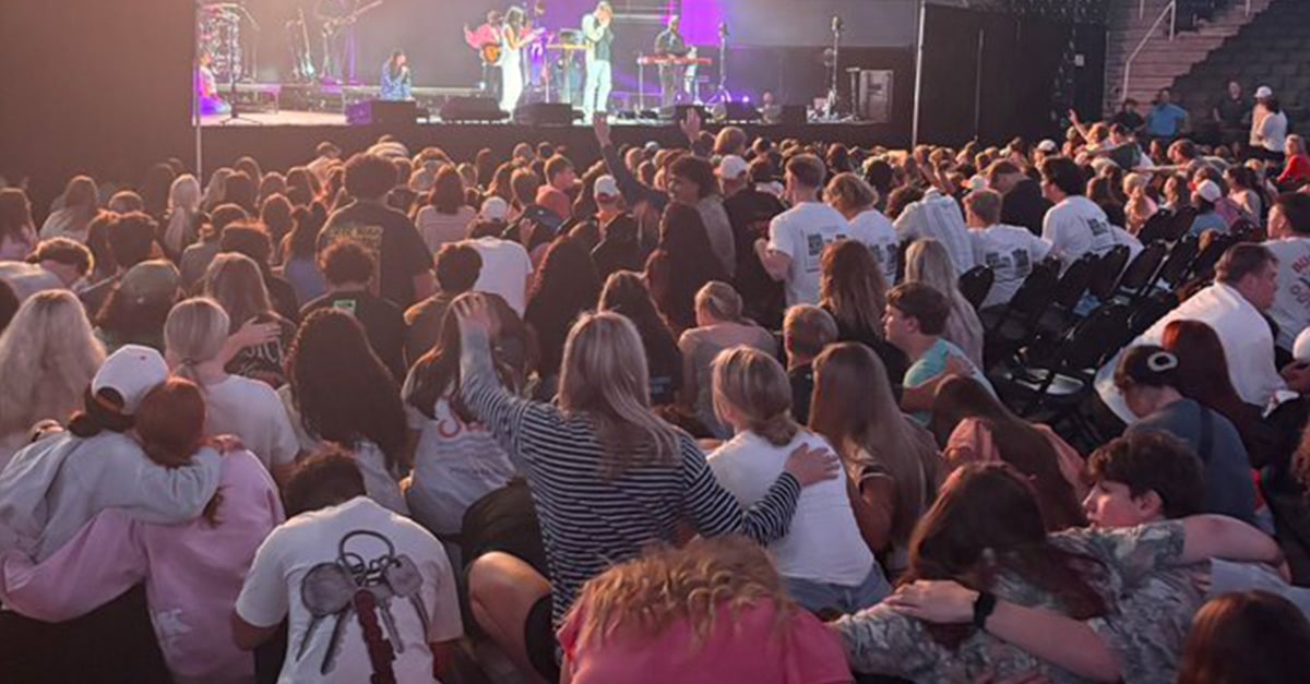 A large crowd of students at the University of Tennessee pray and praise Jesus at a Christian prayer gathering.