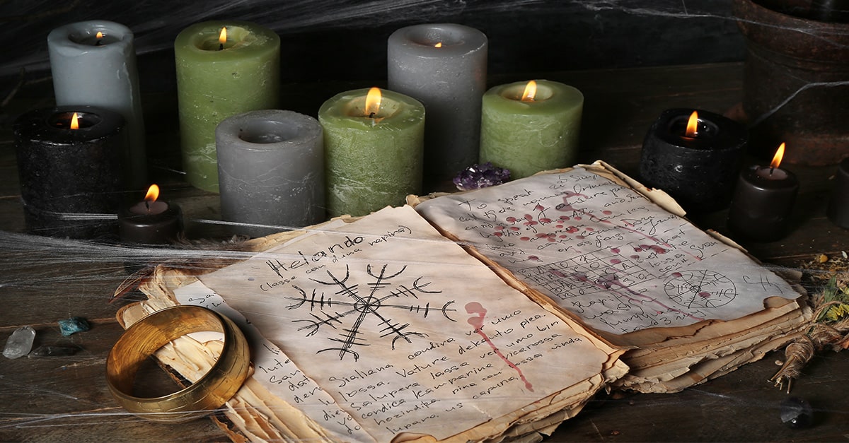 Witchcraft book of spells, candles, witchcraft symbols in dark setting